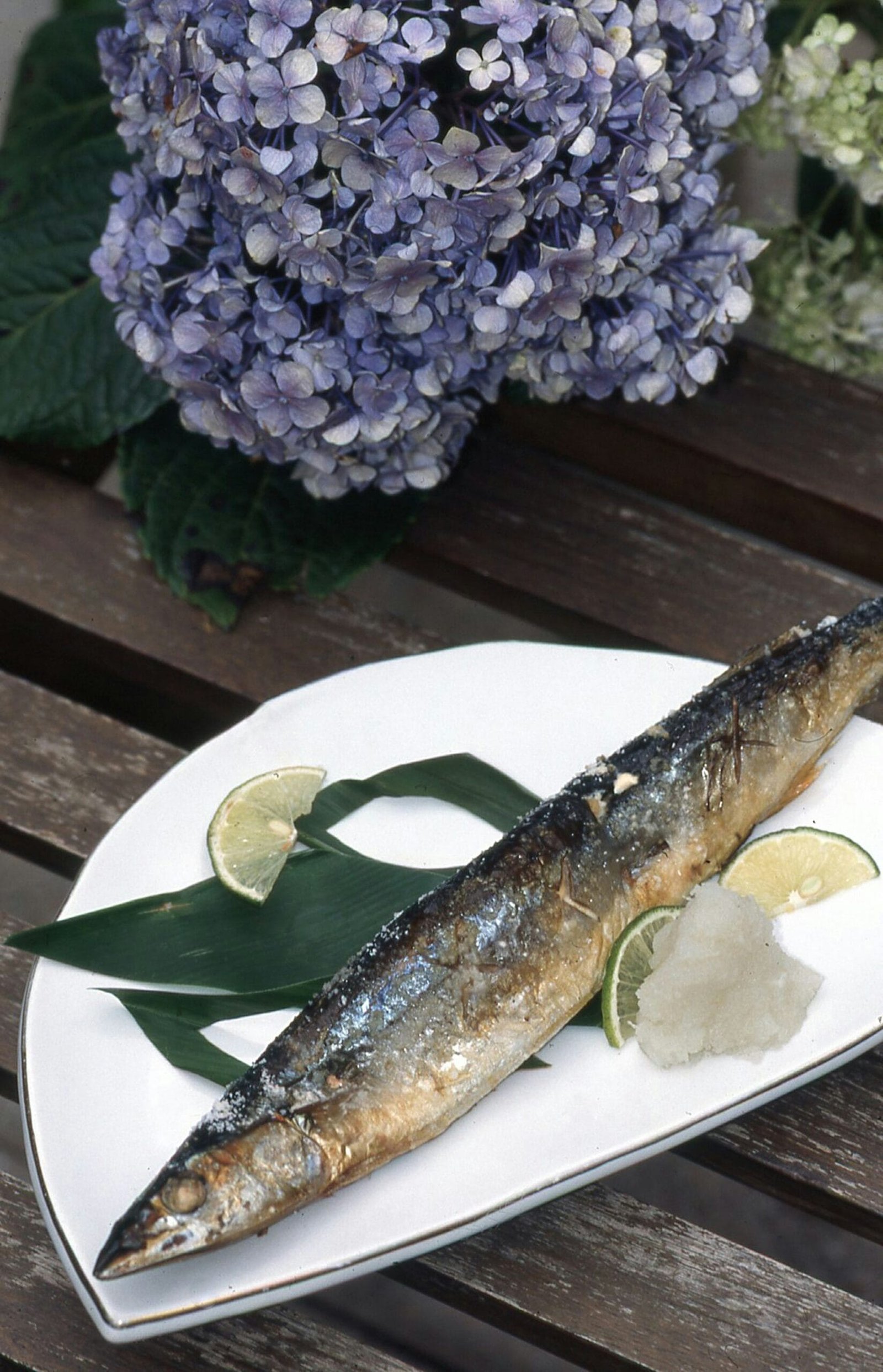 A fish sitting on a plate next to a vase of flowers
